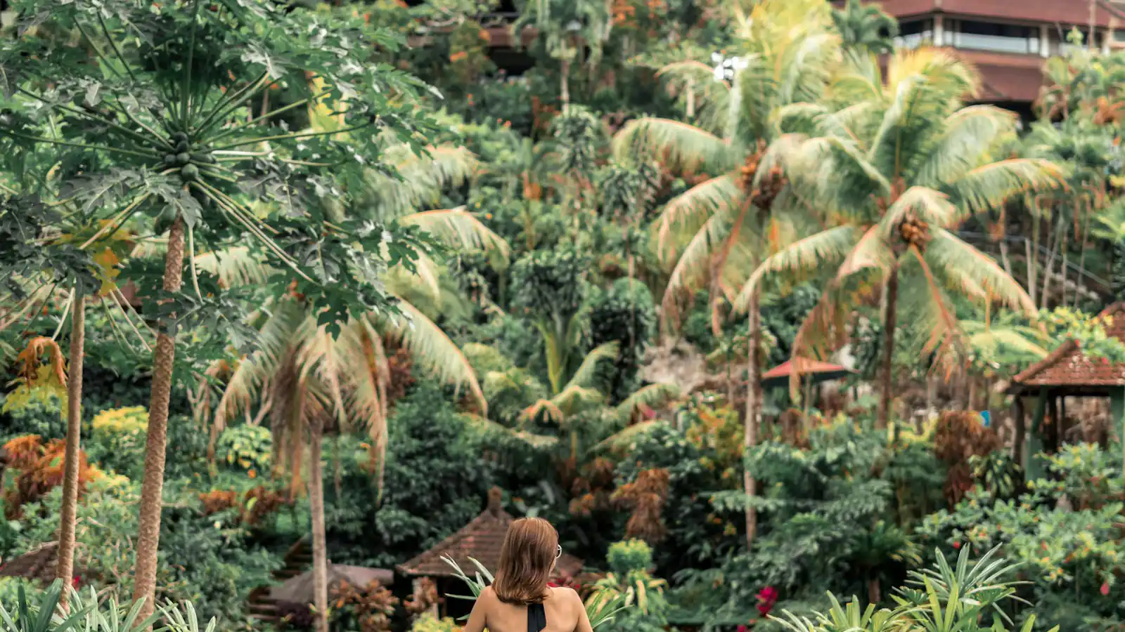 Woman in an infinity pool looking out over jungle