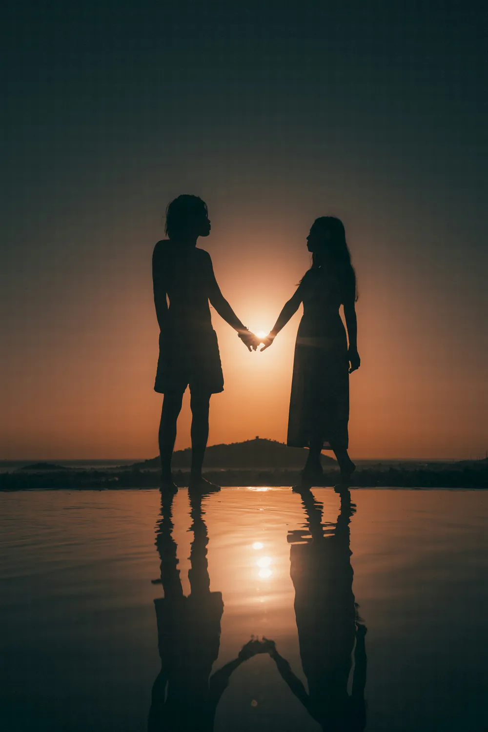 Silhouette of a couple holding hands at sunset